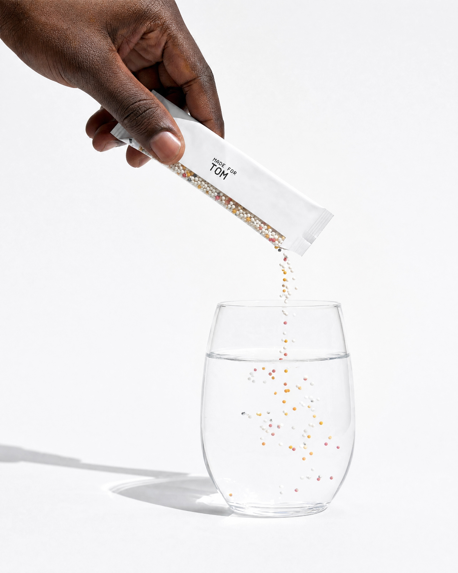Hands holding a glass of water with Lova microgranules dissolving